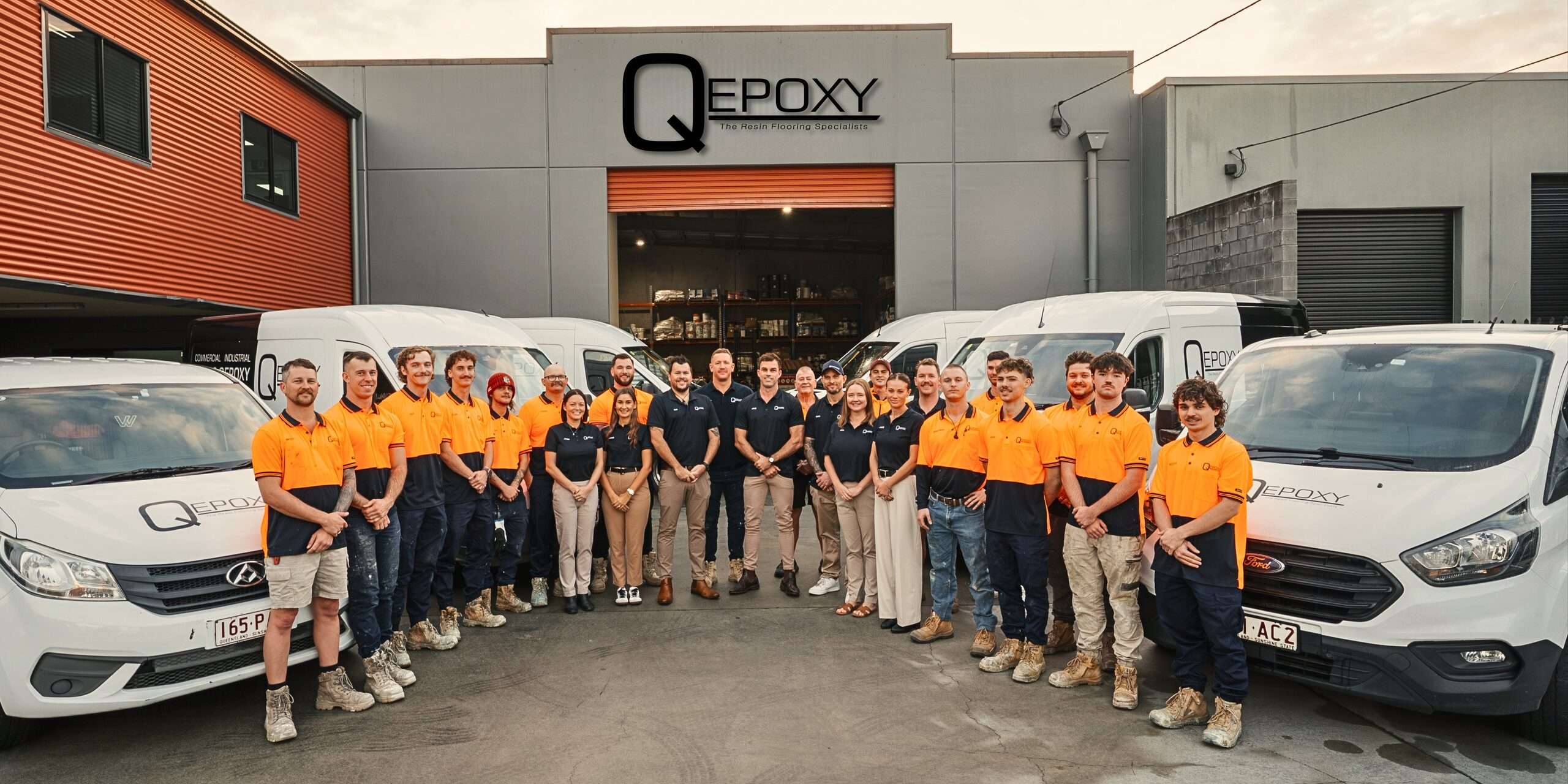 Qepoxy team in front of the Northgate warehouse with branded vans