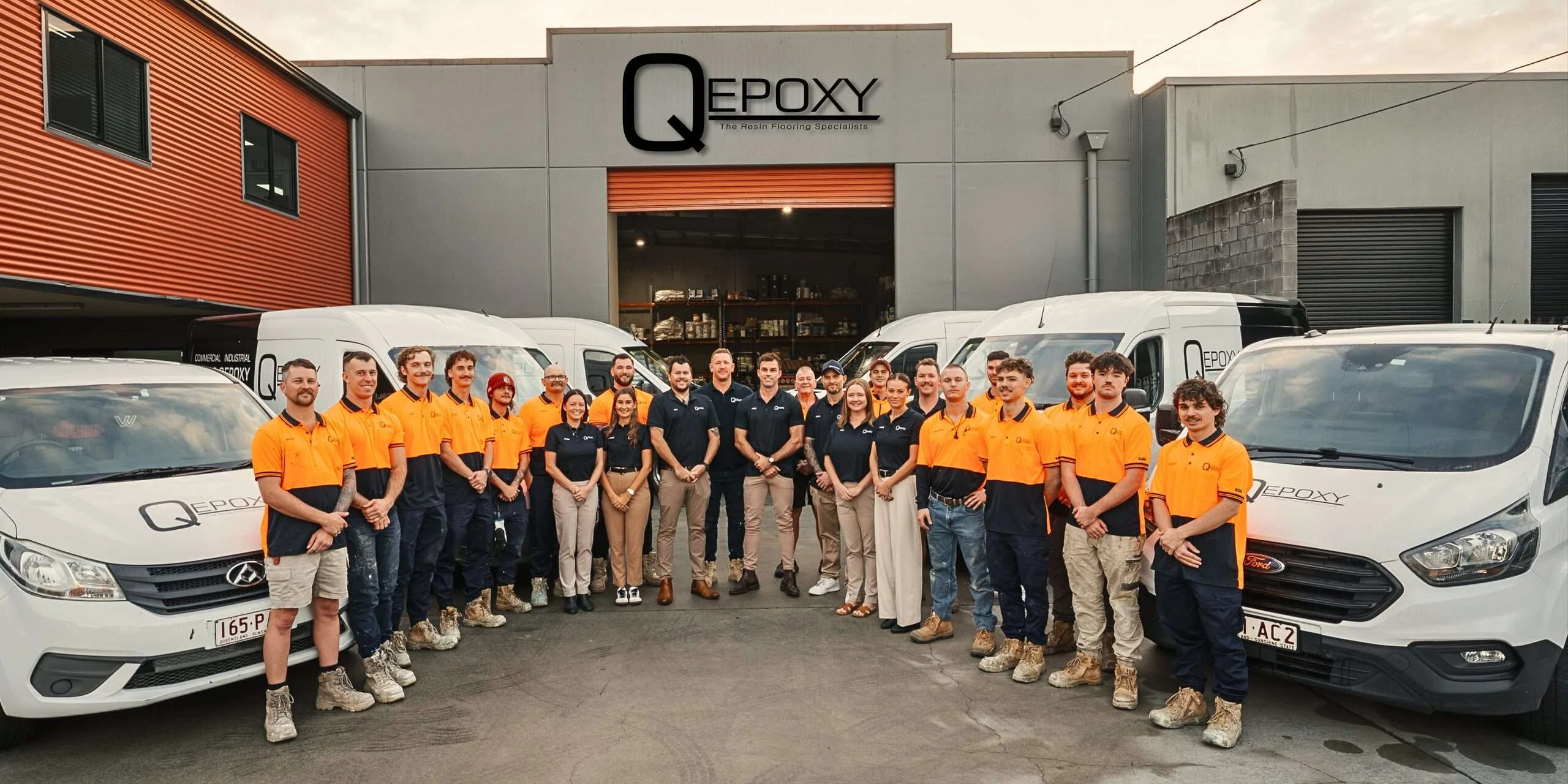 Qepoxy team in front of the Northgate warehouse with branded vans